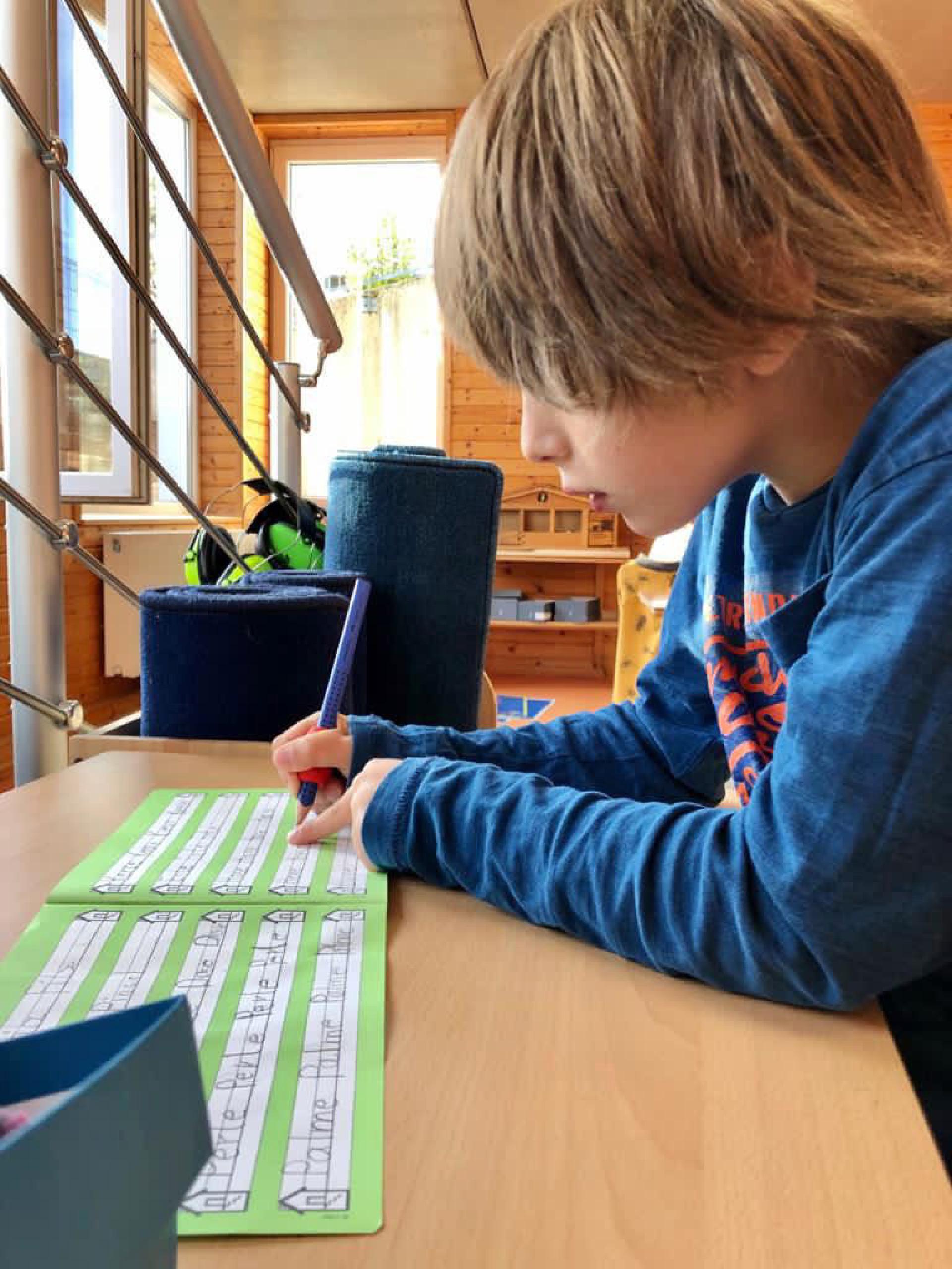 Ein Junge schreibt konzentriert auf ein Blatt Papier