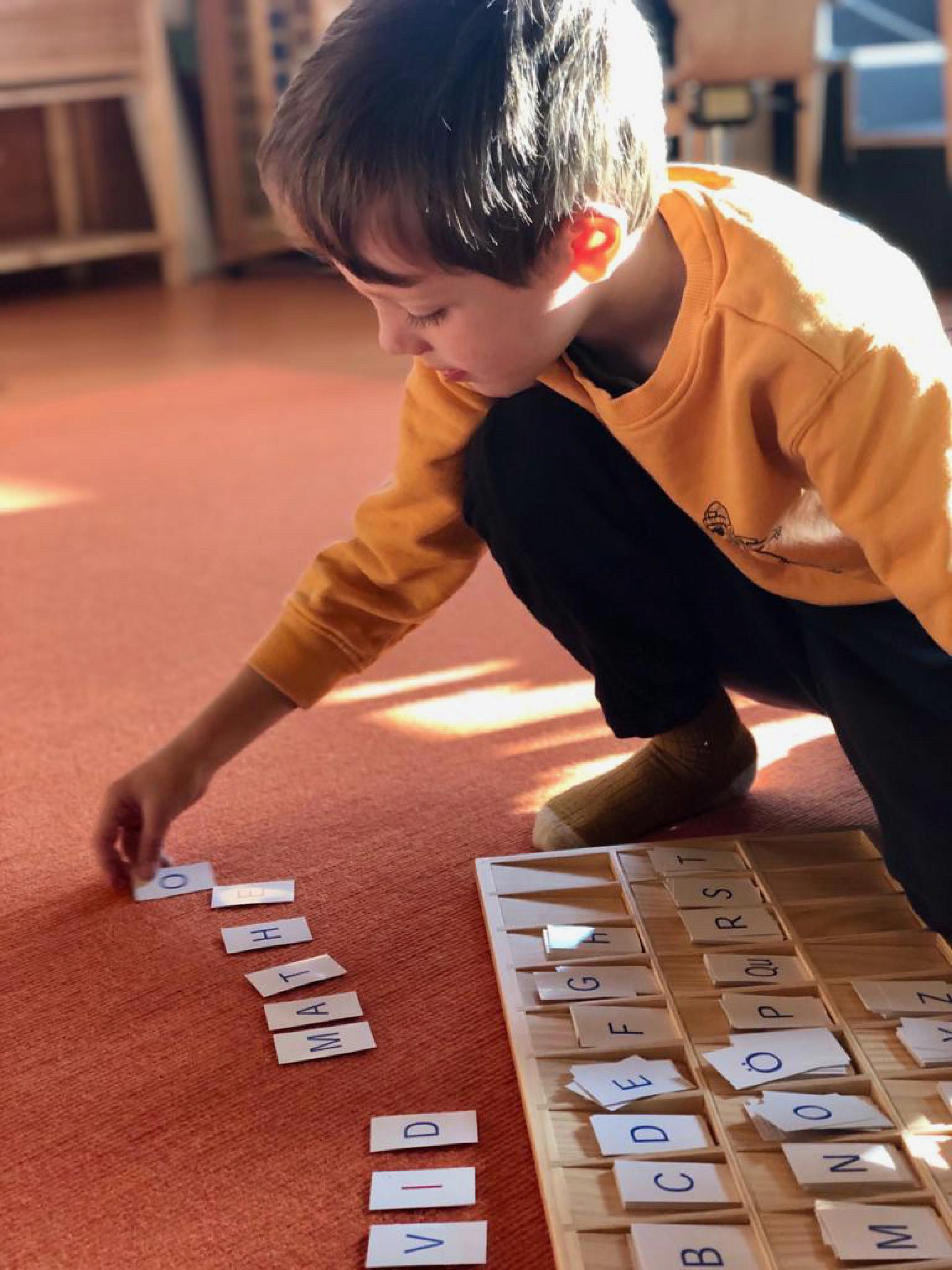 Ein junger Junge spielt mit einem Holzbrett, das mit Buchstaben versehen ist